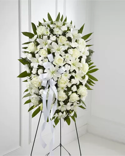 <p>The Exquisite Tribute Standing Spray is an elegant display of sweet serenity. White roses, Asiatic lilies, chrysanthemums and mini carnations are artfully arranged amongst emerald palm fronds and lush greens. Accented by white satin ribbon and standing on a wire easel, this standing spray is an outstanding way to honor the life of your loved one.</p>